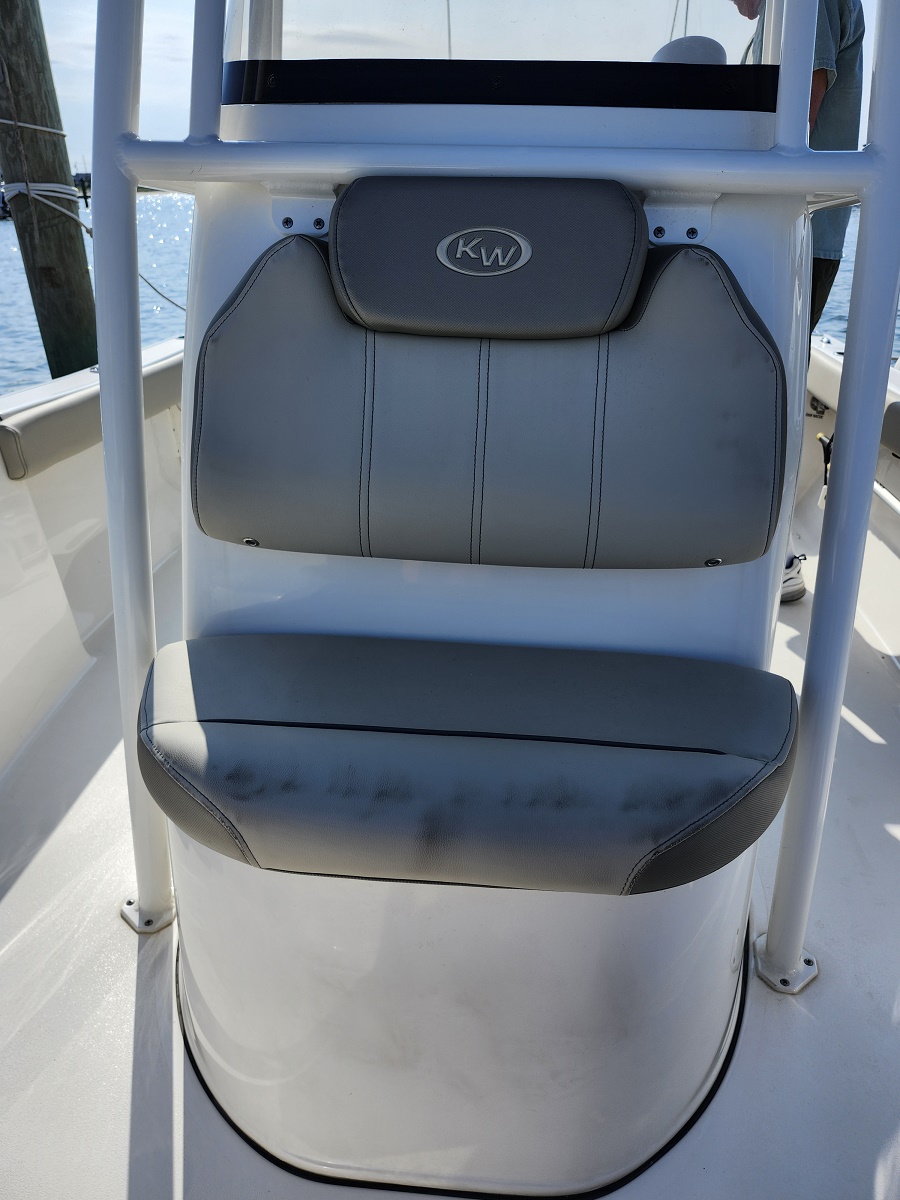 Gray boat chair with a cushioned backrest and headrest labeled 'KW' on a white boat interior, water in the background
