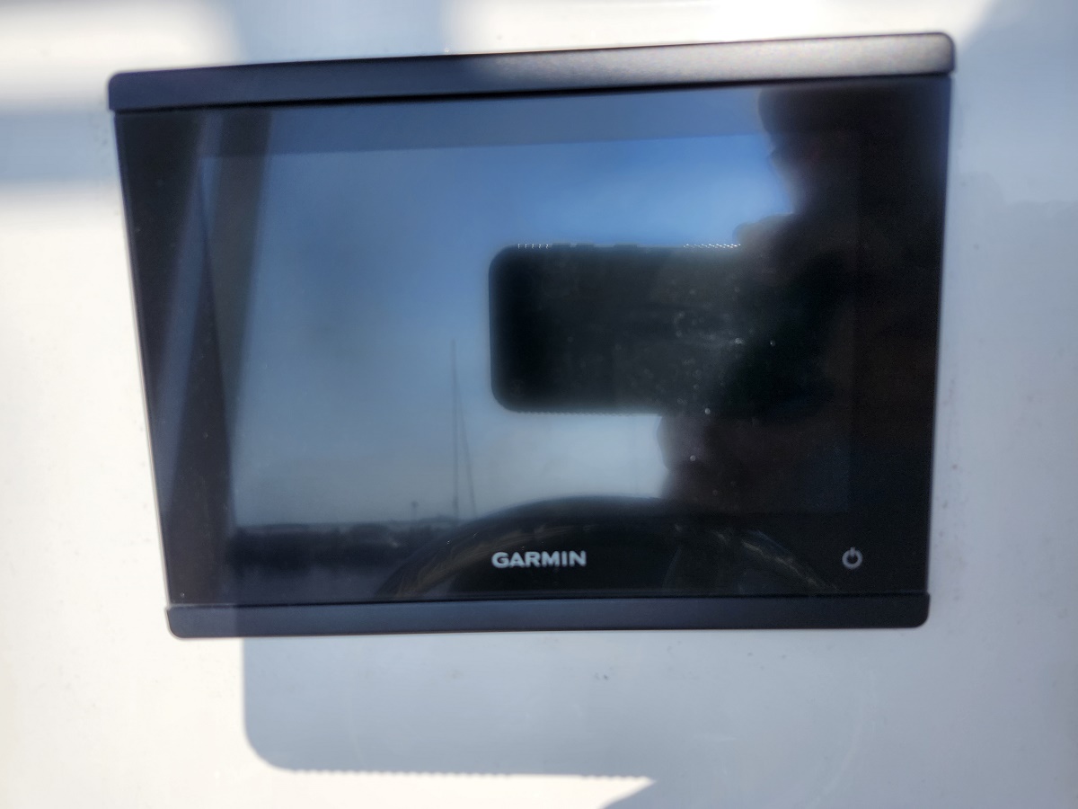 Garmin marine display mounted on boat with blank screen, reflecting the photographer's silhouette