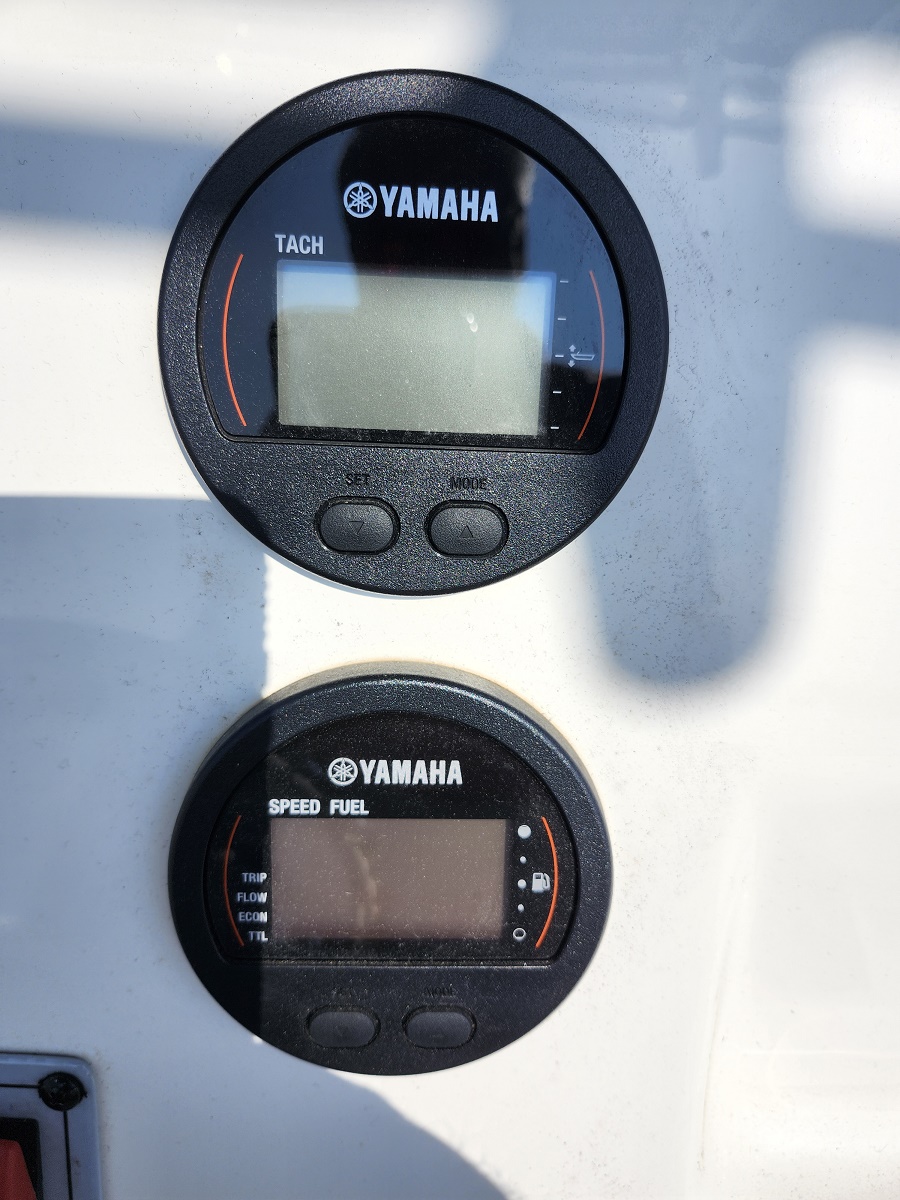 Close-up of a Yamaha boat dashboard showing a tachometer on top and a speed/fuel gauge below on a white panel.