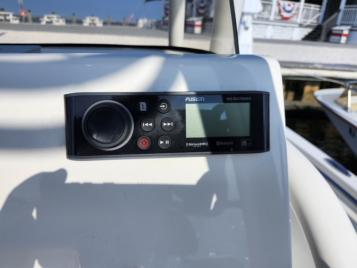 Fusion marine stereo on a boat dashboard with display screen and control buttons