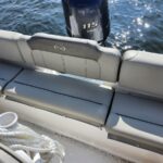 Boat stern seating with gray cushions and backrest, Yamaha 115 outboard visible over blue water behind.