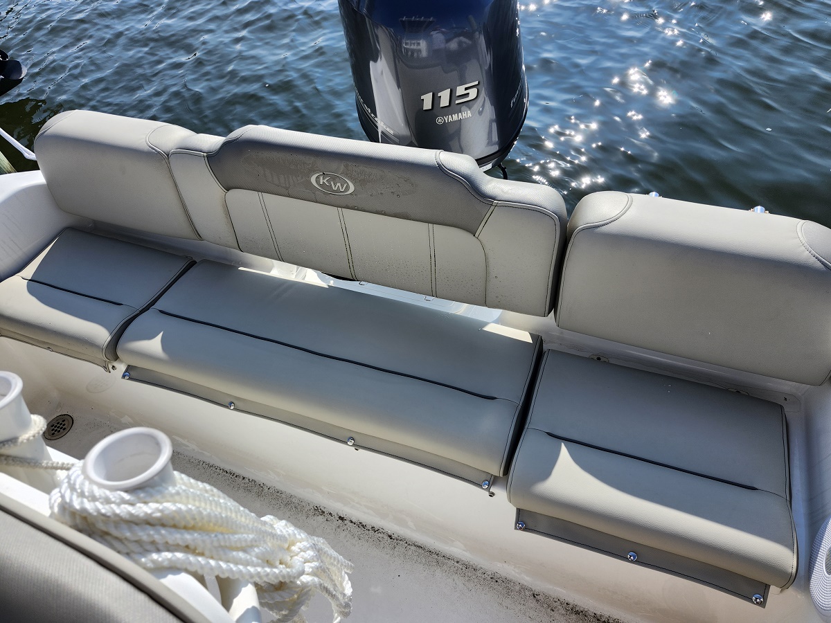 Boat stern seating with gray cushions and backrest, Yamaha 115 outboard visible over blue water behind.