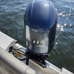 Blue Yamaha 115 outboard motor mounted on the back of a boat with water in the background.