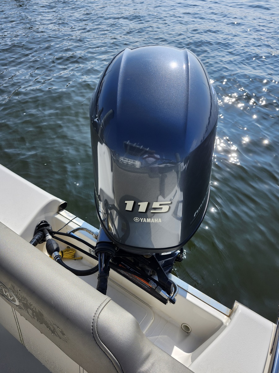 Blue Yamaha 115 outboard motor mounted on the back of a boat with water in the background.